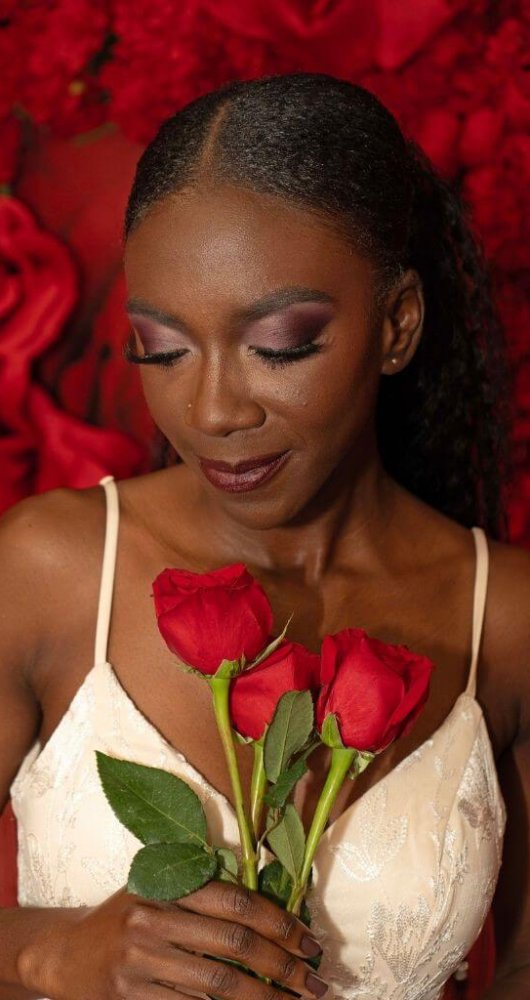 Beautiful woman with dark skin with red roses in wedding dress.